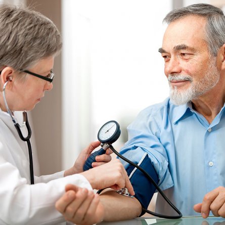 Ärztin misst an einem Patienten den Blutdruck